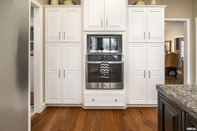 kitchen featuring dark stone countertops, dark hardwood / wood-style floors, white cabinets, and appliances with stainless steel finishes