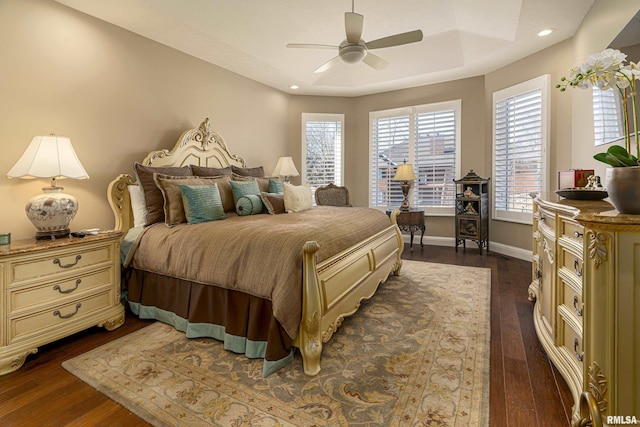 bedroom featuring dark wood-type flooring, ceiling fan, and a tray ceiling