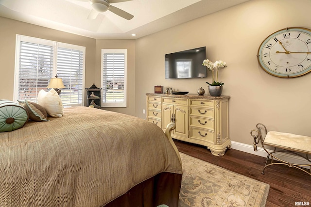 bedroom with a raised ceiling, dark hardwood / wood-style floors, and ceiling fan