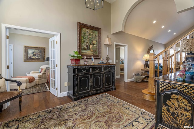 hallway featuring dark wood-type flooring and high vaulted ceiling