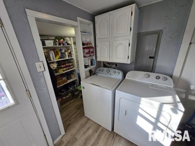 laundry room with cabinets, washing machine and clothes dryer, and light hardwood / wood-style floors