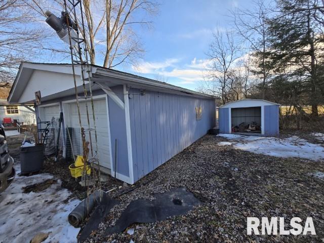 view of snow covered exterior featuring an outbuilding and a garage