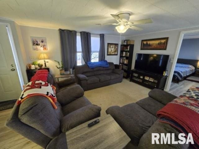 living room featuring ornamental molding, light wood-type flooring, and ceiling fan