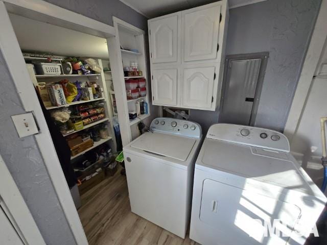 clothes washing area with cabinets, washer and dryer, and light hardwood / wood-style flooring