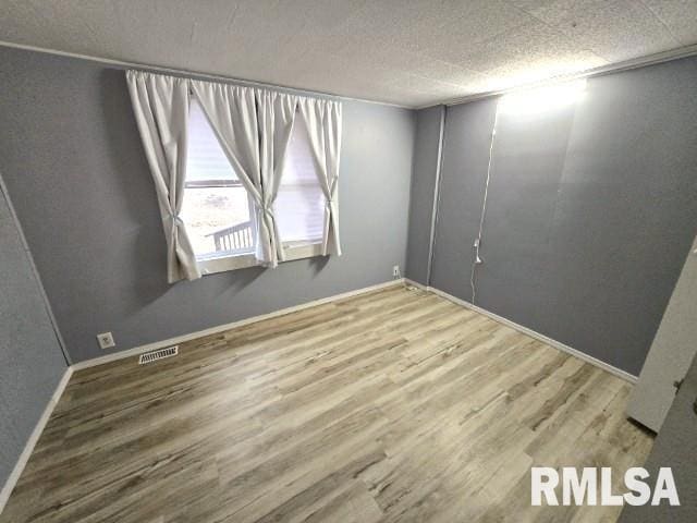 unfurnished room featuring hardwood / wood-style floors and a textured ceiling