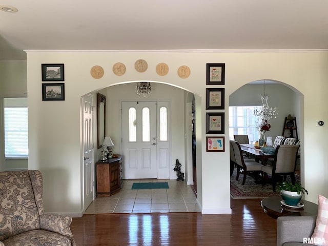 entrance foyer with ornamental molding, a chandelier, and light wood-type flooring