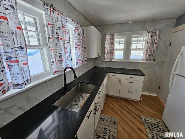 kitchen with white cabinetry, sink, white appliances, and light wood-type flooring