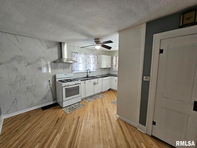 kitchen featuring wall chimney range hood, white appliances, light hardwood / wood-style flooring, sink, and white cabinets