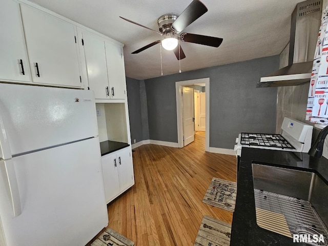 kitchen with white cabinetry, wall chimney range hood, white appliances, and light hardwood / wood-style flooring