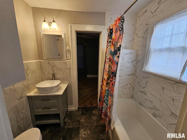 full bathroom featuring vanity, plenty of natural light, tile walls, and shower / tub combo with curtain