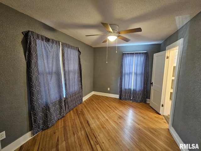 unfurnished bedroom featuring a textured ceiling, ceiling fan, and light wood-type flooring