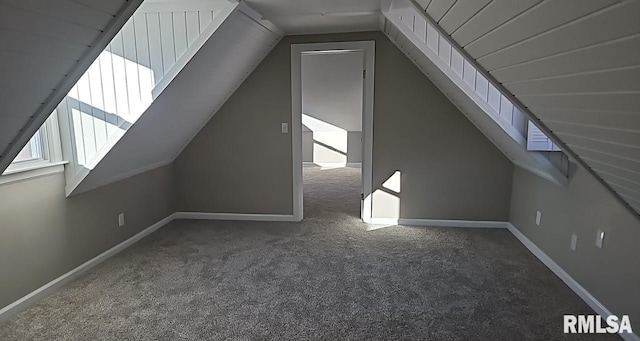 bonus room with vaulted ceiling and dark colored carpet