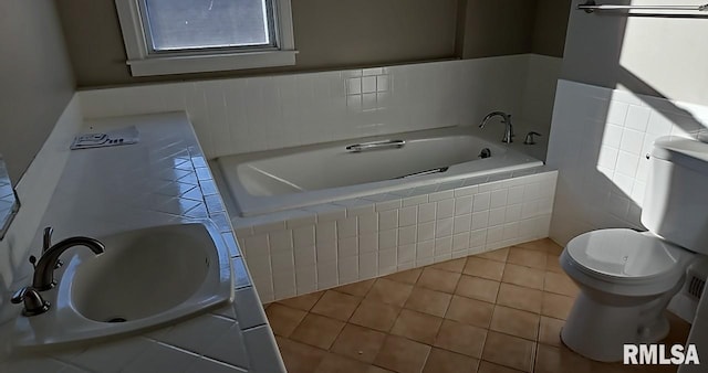 bathroom with a relaxing tiled tub, sink, tile patterned flooring, and toilet