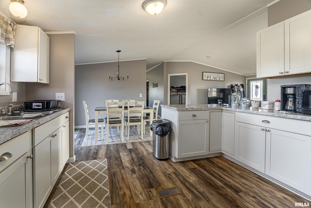 kitchen with pendant lighting, sink, white cabinets, dark hardwood / wood-style flooring, and kitchen peninsula