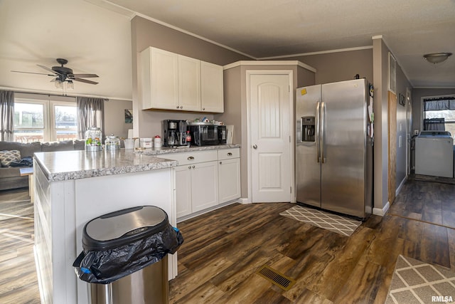 kitchen featuring stainless steel refrigerator with ice dispenser, ornamental molding, washer / clothes dryer, and white cabinets