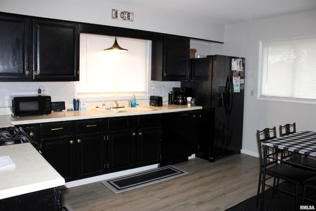 kitchen with hardwood / wood-style floors, sink, pendant lighting, and black appliances