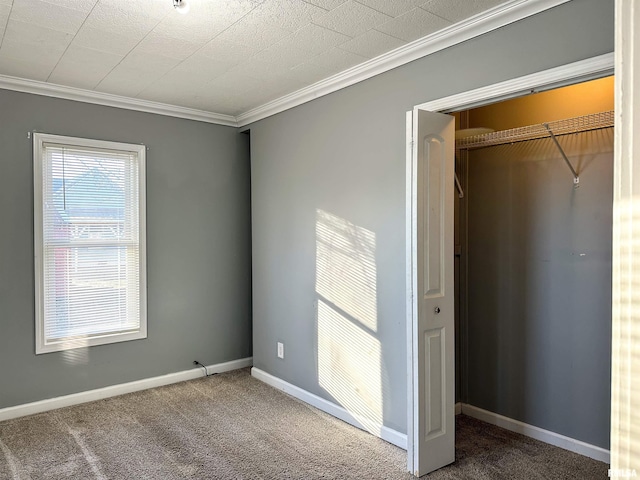 unfurnished bedroom with crown molding, a closet, baseboards, and carpet flooring