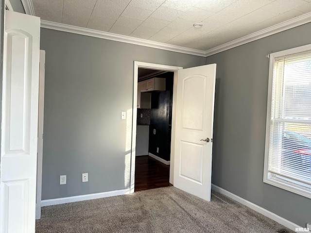 unfurnished bedroom with carpet floors, baseboards, and crown molding