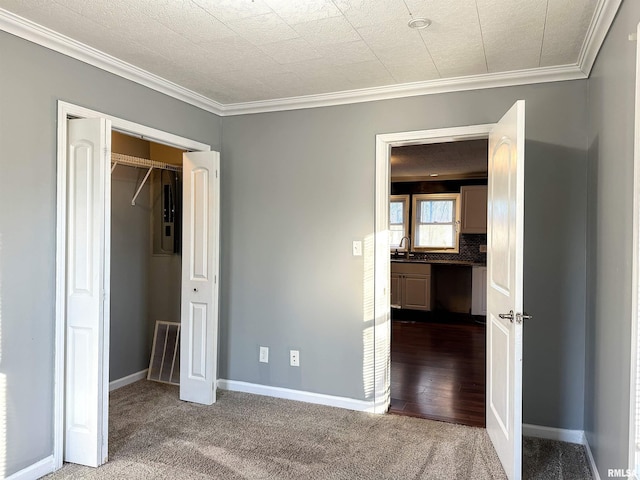 unfurnished bedroom with carpet flooring, a sink, visible vents, baseboards, and ornamental molding