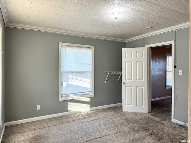 unfurnished bedroom with carpet floors, visible vents, crown molding, and baseboards