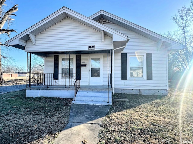 bungalow featuring covered porch and a front yard