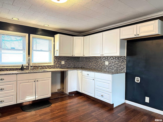 kitchen featuring dark wood-type flooring, crown molding, white cabinets, and a sink