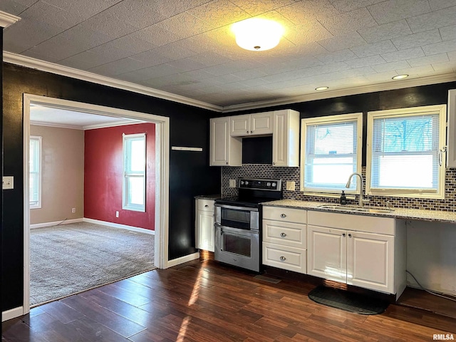 kitchen with range with two ovens, a sink, white cabinetry, and tasteful backsplash