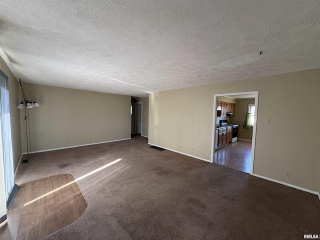 unfurnished room featuring a textured ceiling and dark carpet