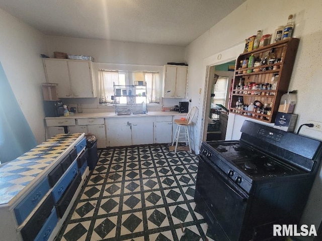 kitchen with white cabinetry, sink, and gas stove