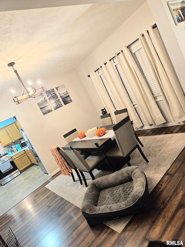 dining space featuring hardwood / wood-style flooring, a notable chandelier, and a textured ceiling