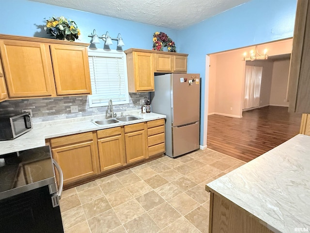 kitchen with sink, decorative light fixtures, a textured ceiling, stainless steel appliances, and decorative backsplash