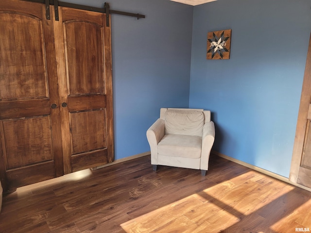 sitting room with dark wood-type flooring and a barn door