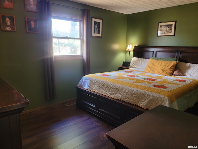 bedroom with dark hardwood / wood-style floors and a textured ceiling