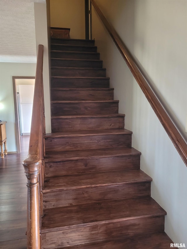 stairs featuring hardwood / wood-style floors and a textured ceiling