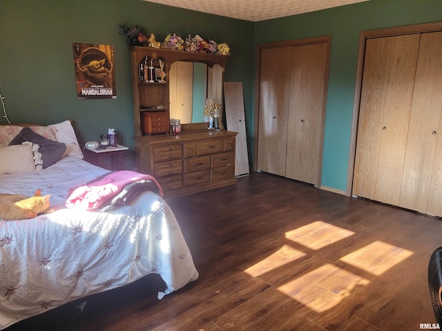 bedroom featuring multiple closets and dark hardwood / wood-style floors