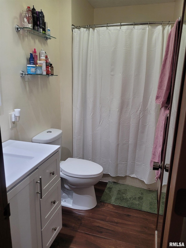 bathroom with wood-type flooring, curtained shower, vanity, and toilet