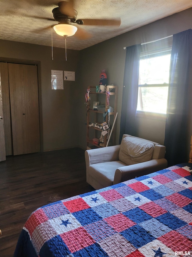 bedroom with ceiling fan, a textured ceiling, dark hardwood / wood-style flooring, and a closet