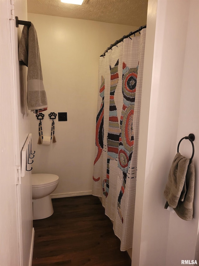 bathroom with hardwood / wood-style floors, a textured ceiling, curtained shower, and toilet