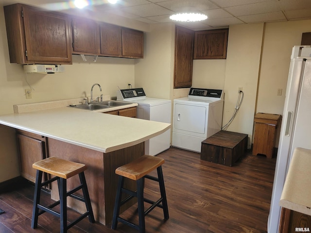 laundry room with sink, dark wood-type flooring, washing machine and dryer, and cabinets