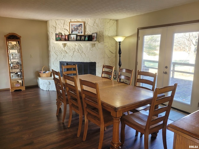 dining space with french doors, a stone fireplace, dark hardwood / wood-style flooring, and a textured ceiling