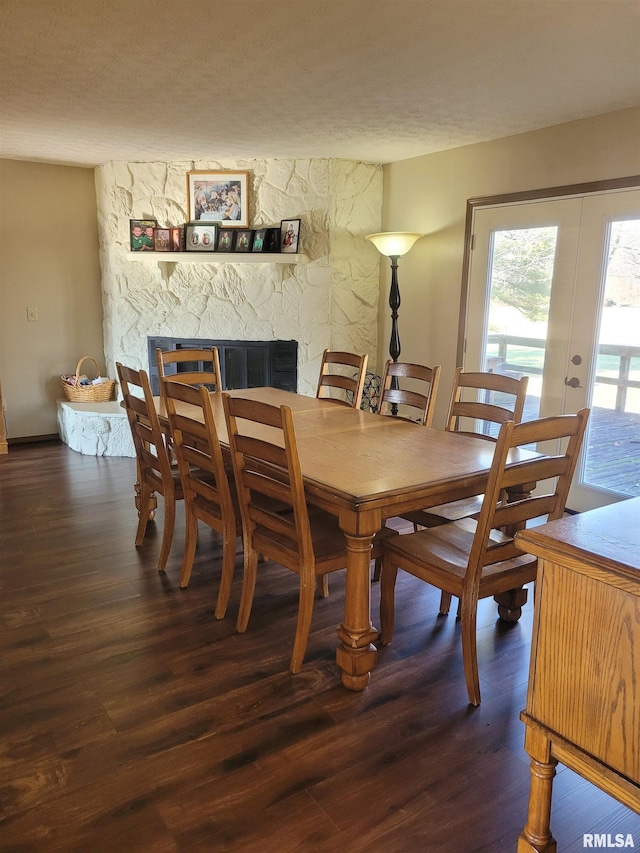 dining space with dark hardwood / wood-style floors, a fireplace, french doors, and a textured ceiling