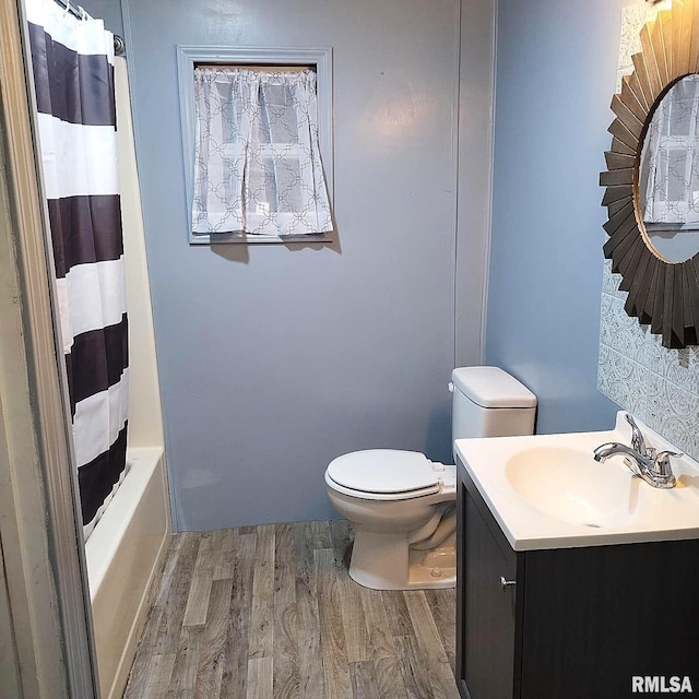 full bathroom featuring vanity, wood-type flooring, toilet, and shower / bathtub combination with curtain