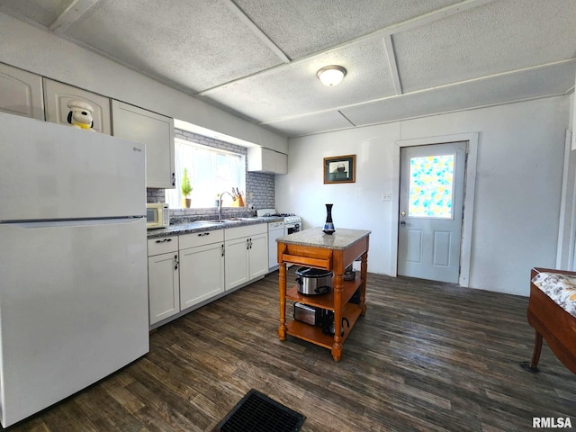 kitchen with dark hardwood / wood-style flooring, sink, white cabinets, and white appliances