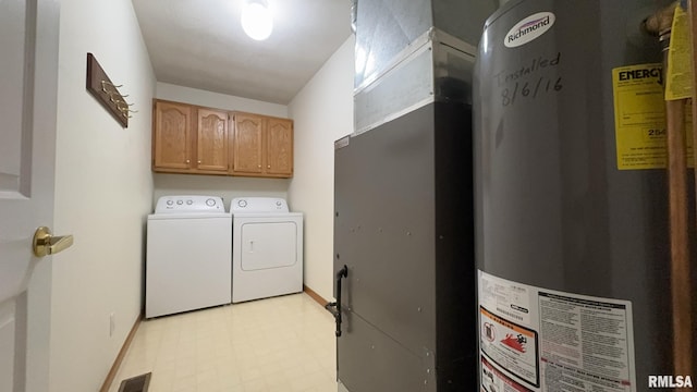 washroom with water heater, cabinets, and washer and clothes dryer