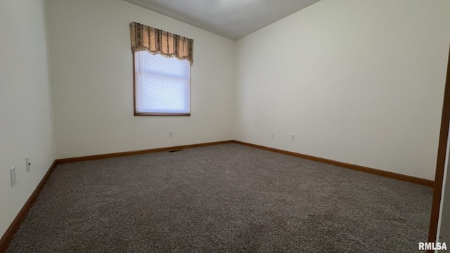 spare room with lofted ceiling and dark carpet