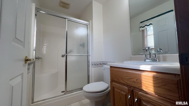 bathroom with vanity, a shower with door, and toilet