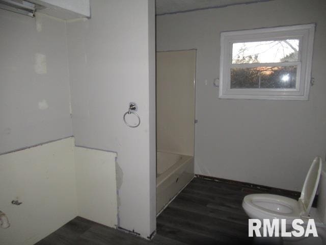 bathroom featuring hardwood / wood-style flooring, toilet, and bathtub / shower combination