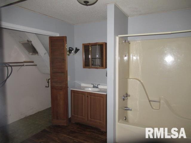 bathroom featuring vanity, hardwood / wood-style flooring, shower / washtub combination, and a textured ceiling