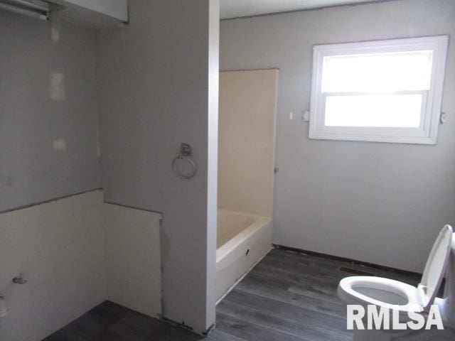 bathroom with wood-type flooring, plus walk in shower, and toilet