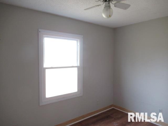 spare room featuring dark wood-type flooring and ceiling fan